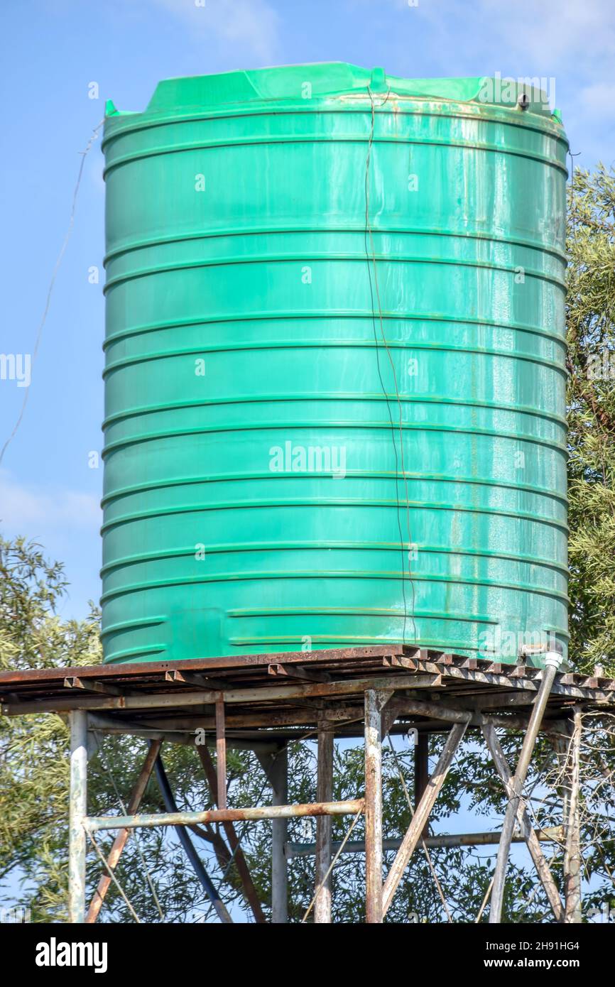 Green plastic water tank or container on an elevated metal structure or tower for pressure commonly used in Southern Africa for household water storag Stock Photo