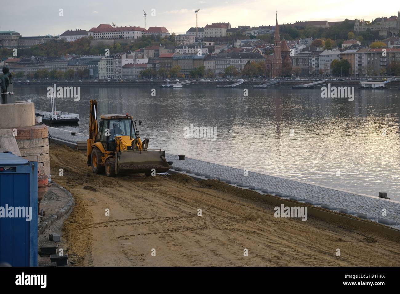 Budapest, Hungary - 1 November 2021: Construction or repair of a road on the Danube river embankment, excavator with a worker, Illustrative Editorial. Stock Photo