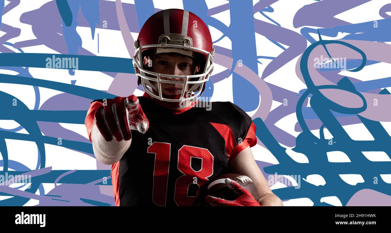 Determined male american football player with ball pointing against abstract background Stock Photo