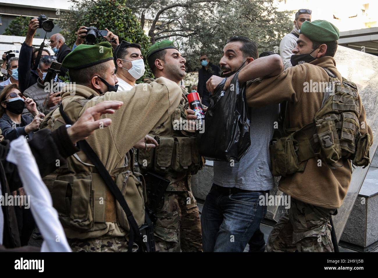 Beirut, Lebanon. 03rd Dec, 2021. Lebanese army soldiers scuffle with an anti-government activist after spraying slogans on the facade of a local bank during a protest against the sky-rocketing price of the US dollar, while demanding the banking sector to lift restrictions on money trapped under informal capital controls. Credit: Marwan Naamani/dpa/Alamy Live News Stock Photo