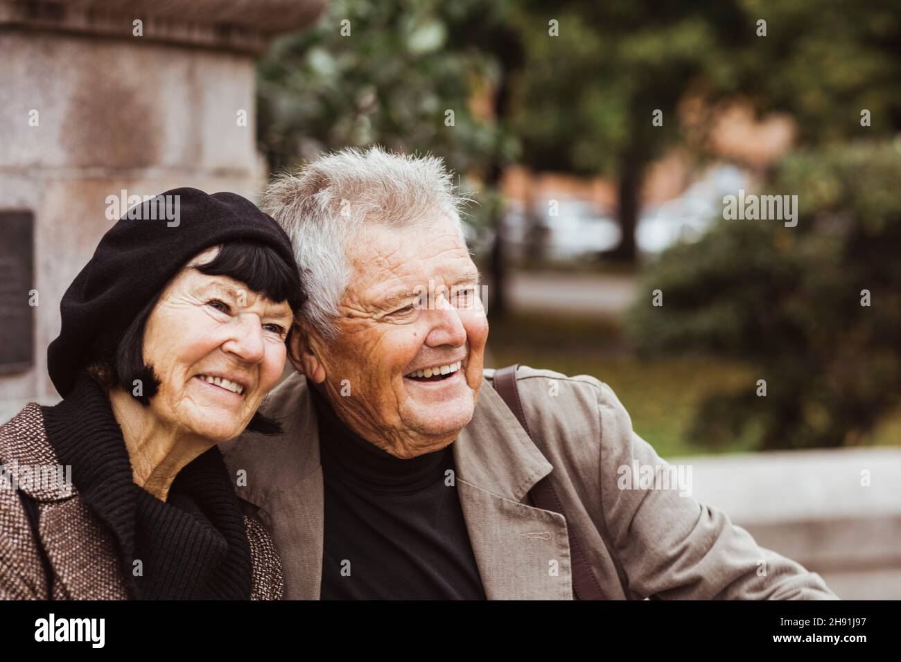 Cheerful senior couple looking away while sitting in park Stock Photo