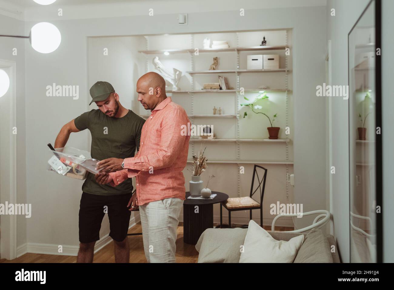Male technician and mature man discussing over document at home Stock Photo