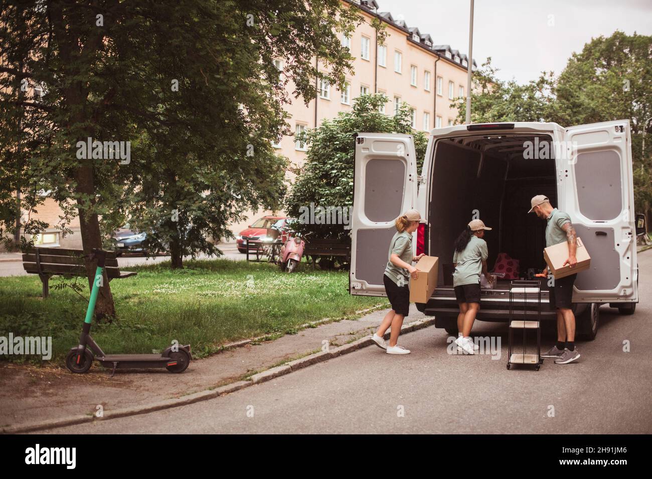 Male and female coworkers loading boxes in delivery van Stock Photo