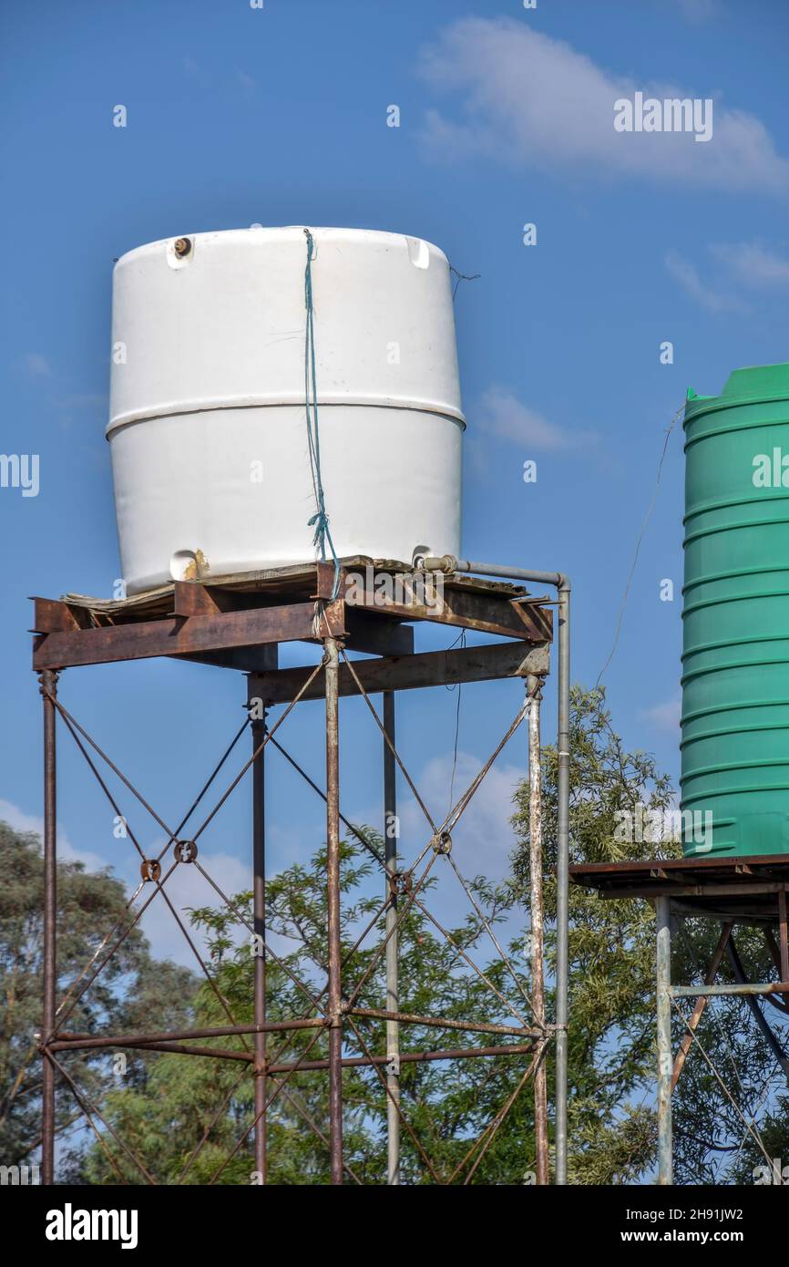 Green and white plastic water tanks or containers on an elevated metal structure or tower for pressure commonly used in Southern Africa for household Stock Photo