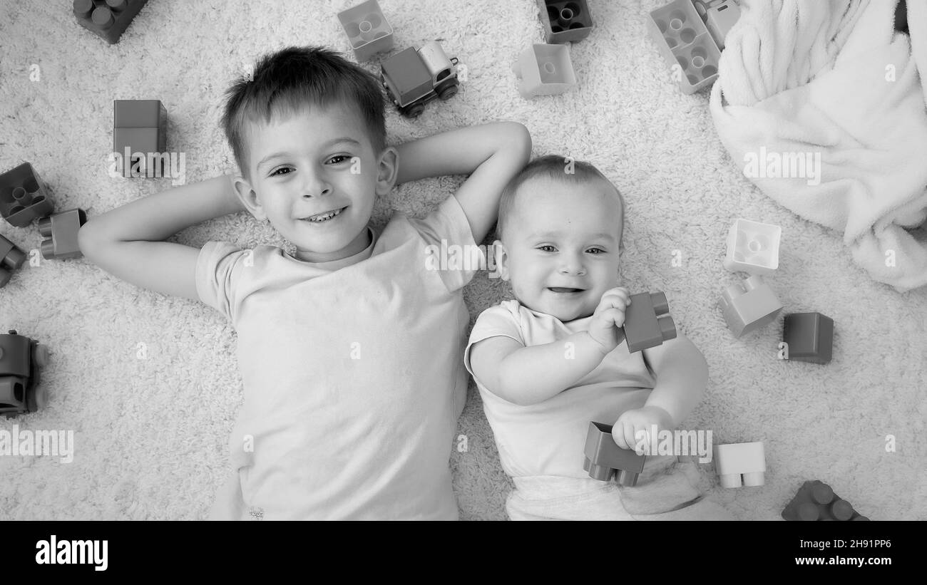 Black and white image of cheerful smiling boy with baby brother