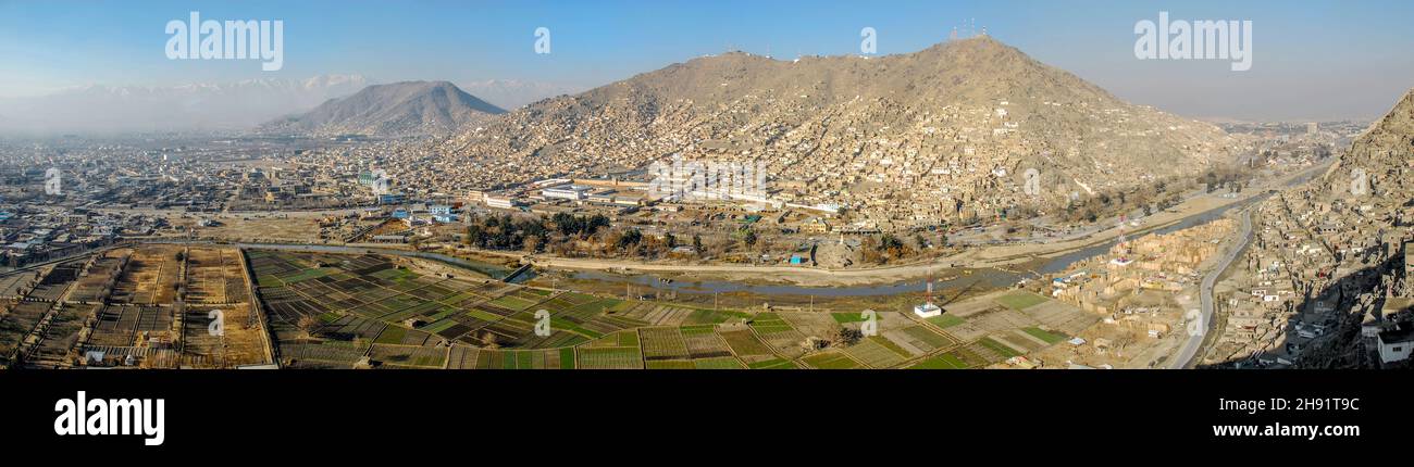 A wide angle panorama of the city center of Kabul with its surrounding hillsides and informal settlements in large agricultural area near the river Stock Photo