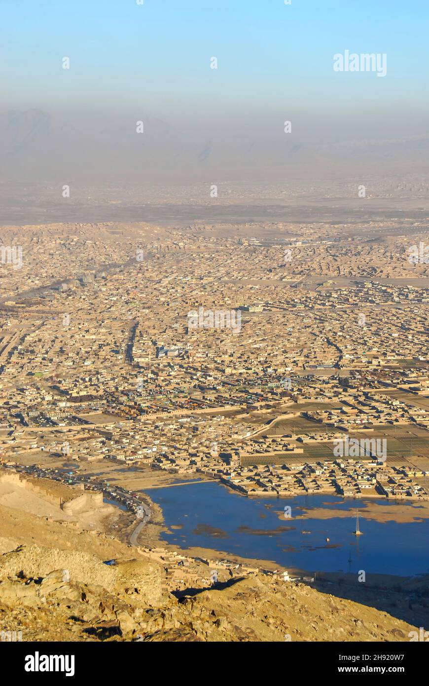 A view of the lake inside the boundaries of Kabul city surrounded by the hillsides with its informal settlements and mountain ranges with pollution in Stock Photo