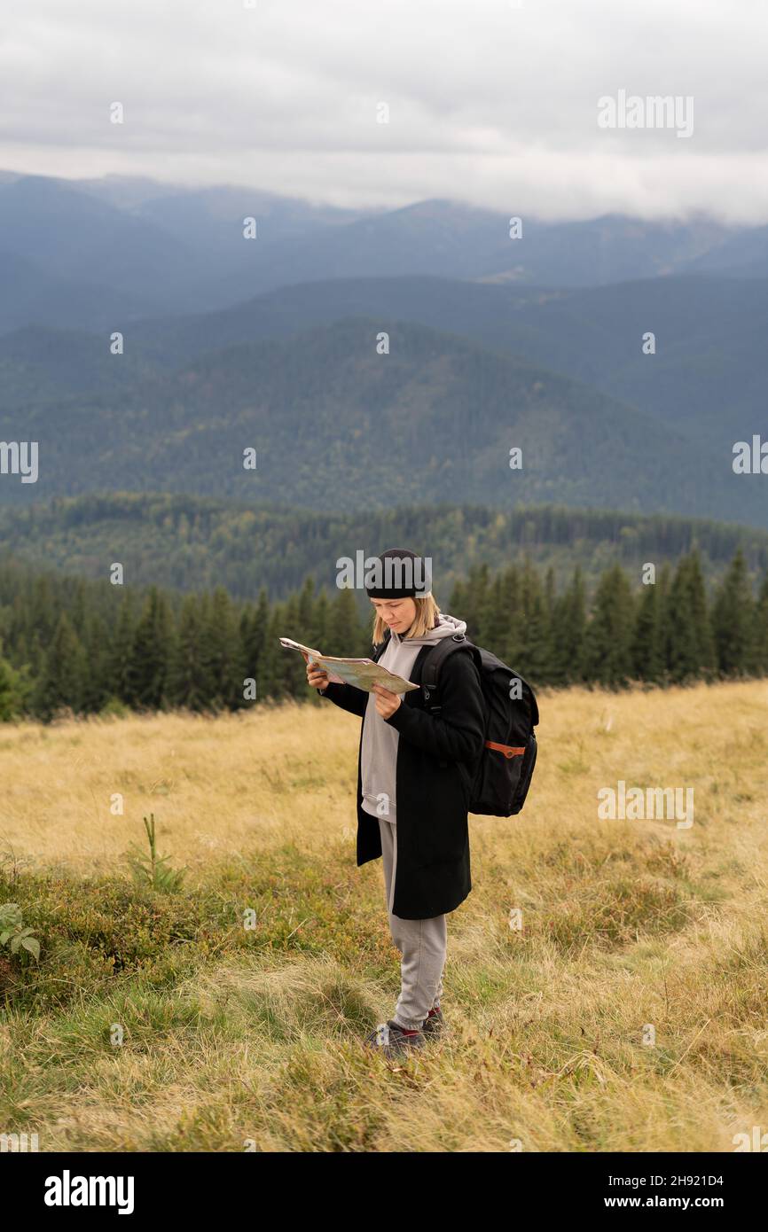 girl tourist in the mountain reading the map, trip through the mountains of europe, hiking rough terrain, hike and trekking, tourism concept. Stock Photo