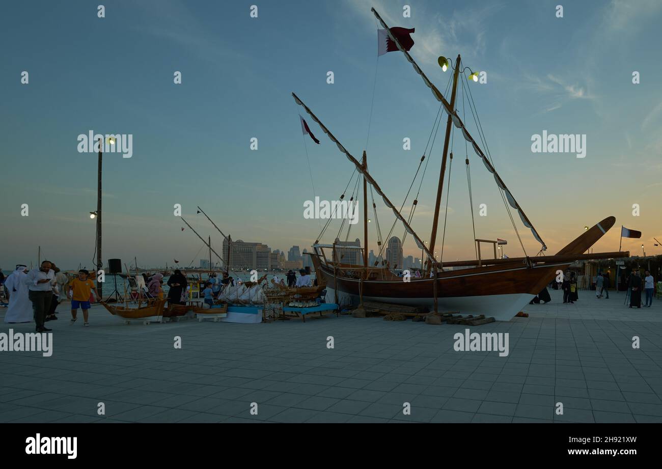 Katara eleventh traditional dhow festival in Doha Qatar sunset shot showing  dhow with Qatar Flags on display on the beach with locals and visitors Stock Photo