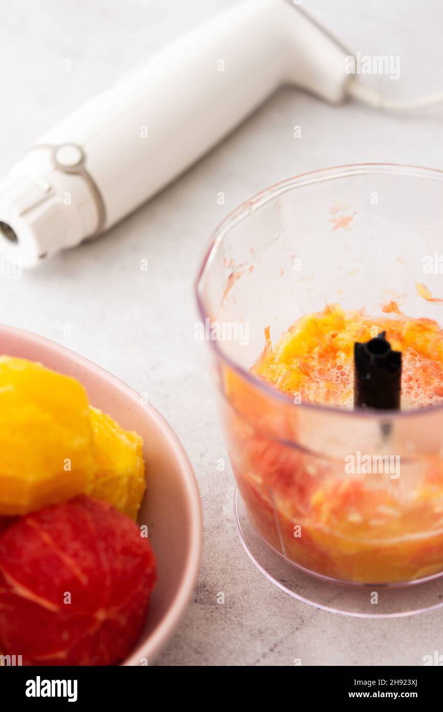 Peeled grapefruits, sweets and oranges in a plate, blender bowl with fruit, making a healthy