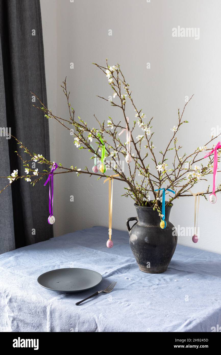 Blooming cherry branches decorated with colorful ribbons with easter eggs, Happy Easter, table setting Stock Photo