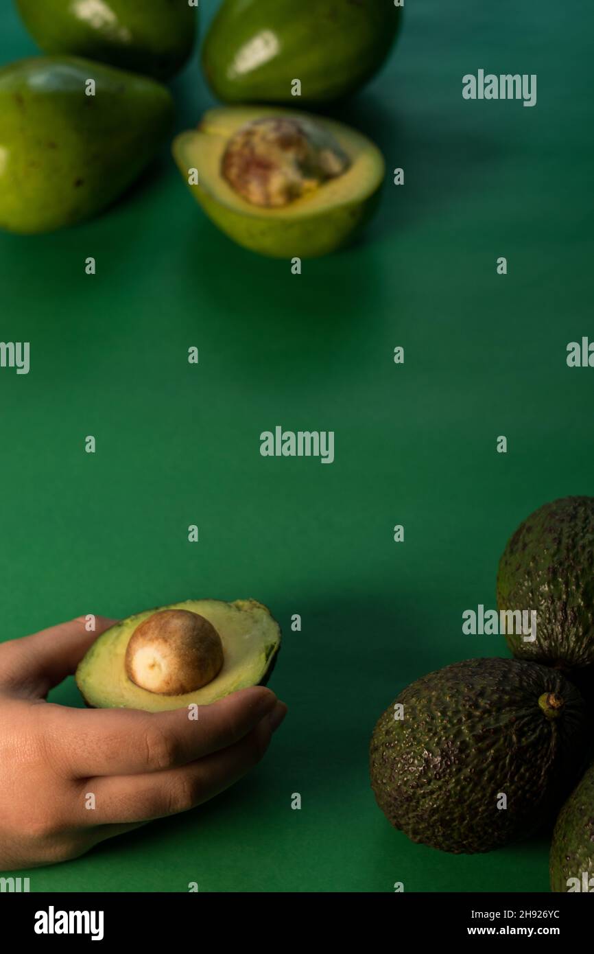 Some fresh avocados and hass avocado on a green background Stock Photo