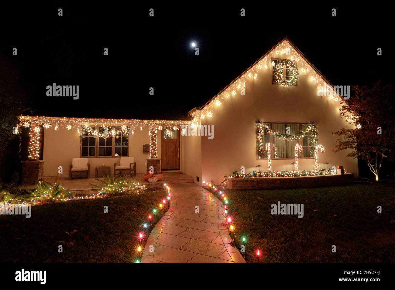 Christmas lights decorating house at night with full moon Stock Photo