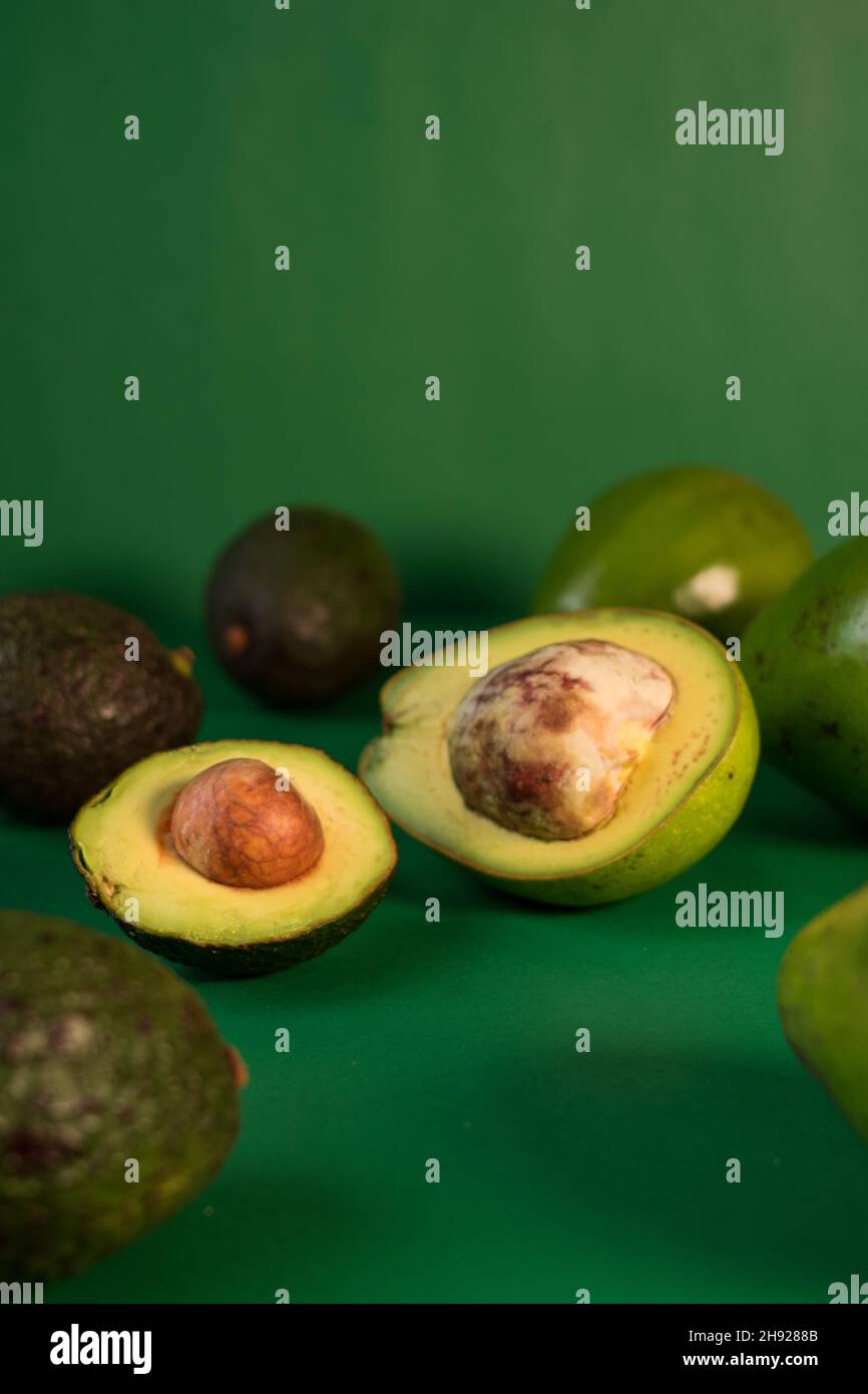 Some fresh avocados and hass avocado on a green background Stock Photo