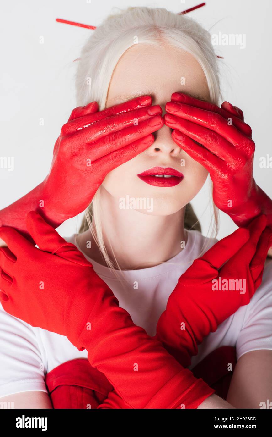 Female hands in red paint covering eyes of albino model isolated on white  Stock Photo - Alamy