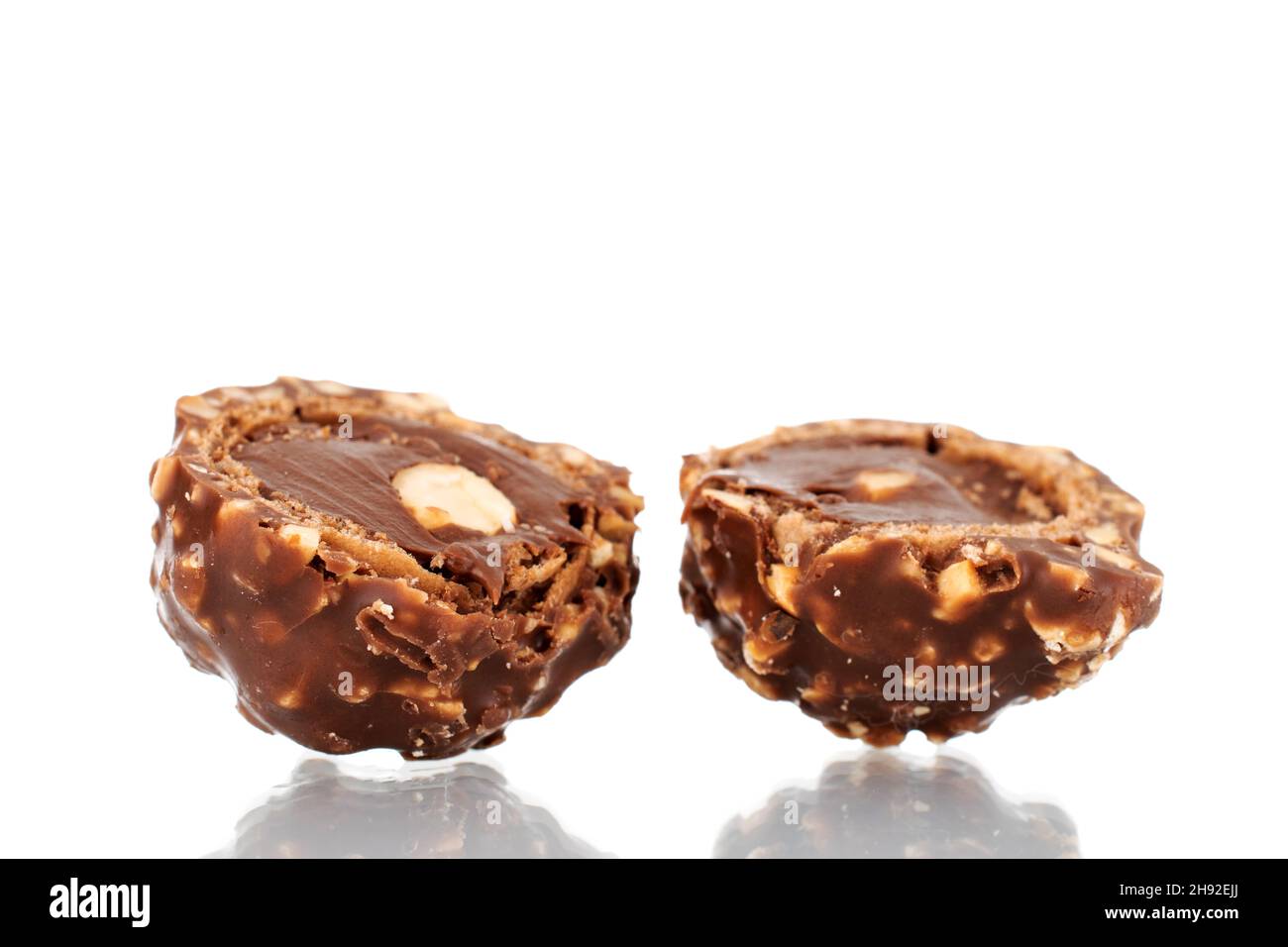 Two halves of chocolate candy with nuts, close-up, isolated on white. Stock Photo