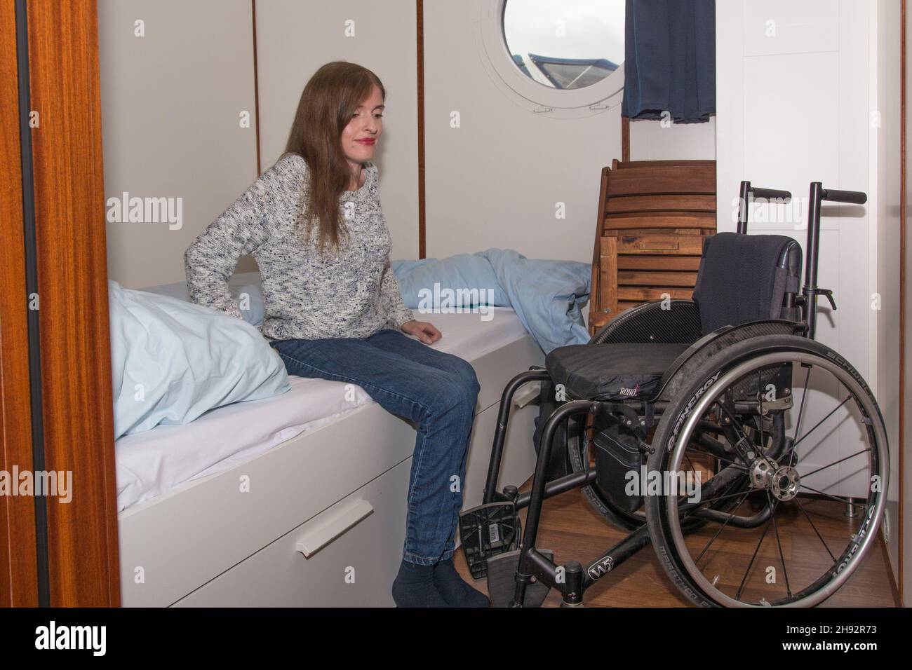 Frau im Rollstuhl auf Hausboot setzt sich um ins Bett Stock Photo