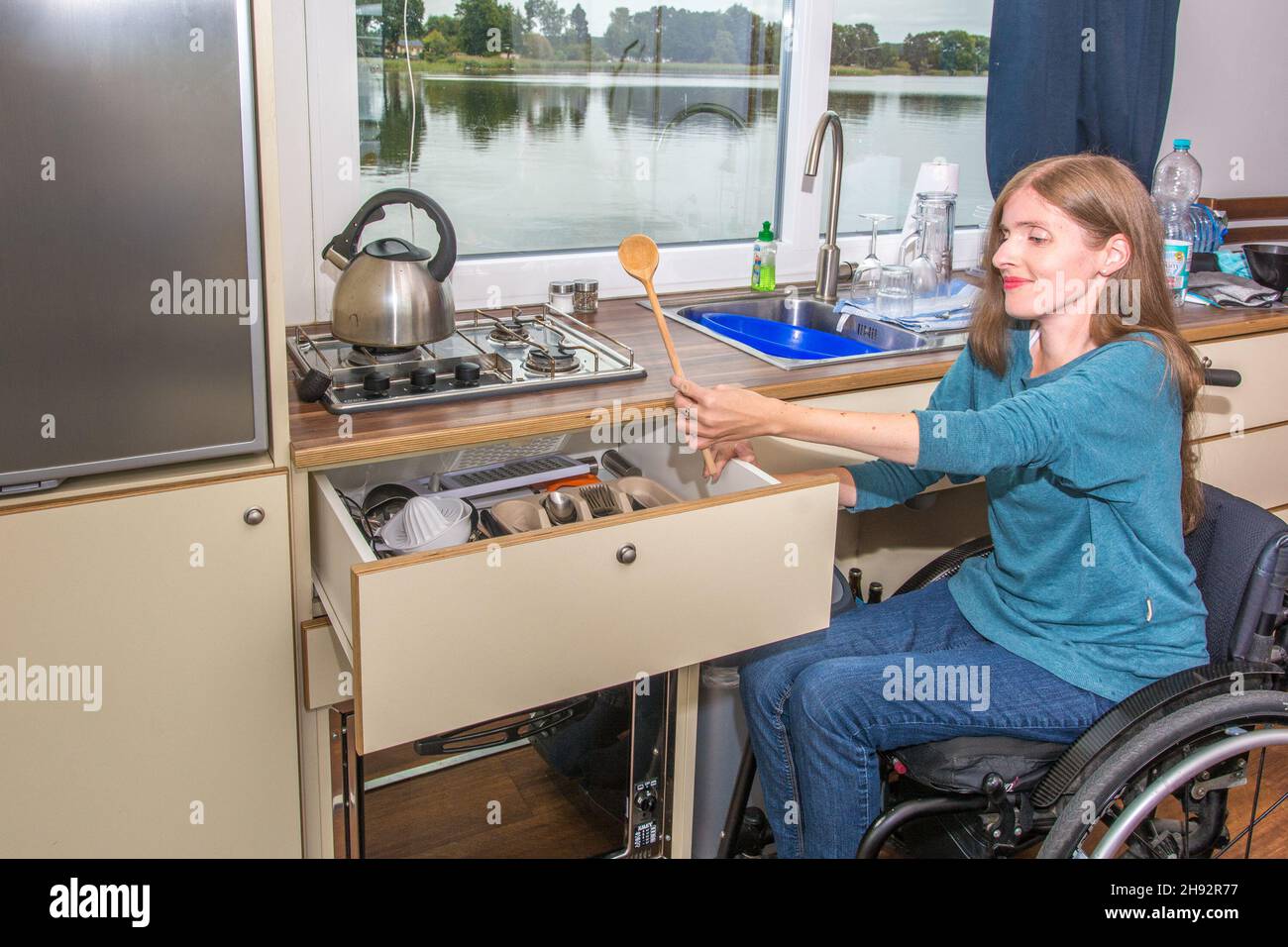 Frau im Rollstuhl auf Hausboot macht Abwasch Stock Photo