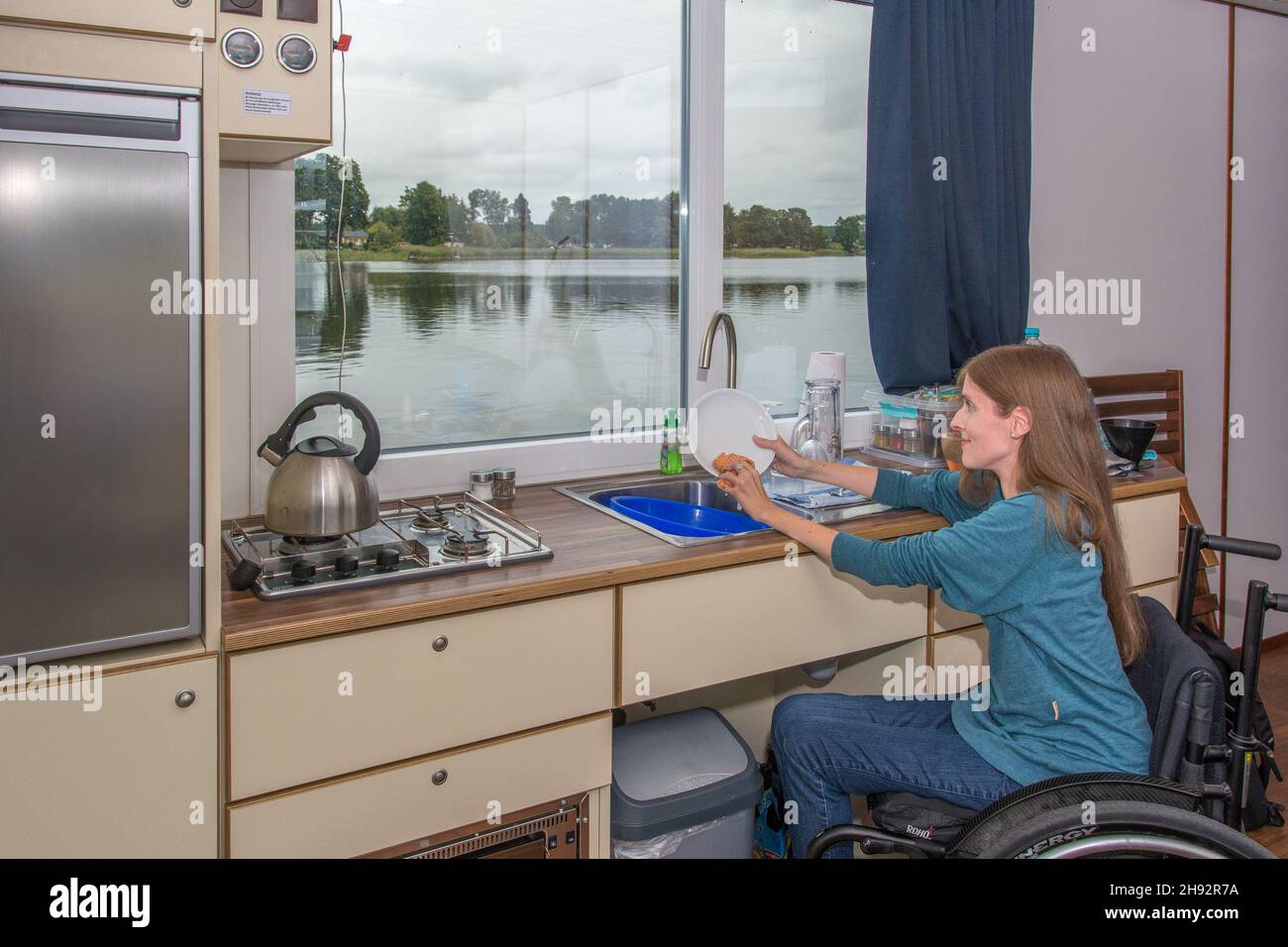 Frau im Rollstuhl auf Hausboot macht Abwasch Stock Photo