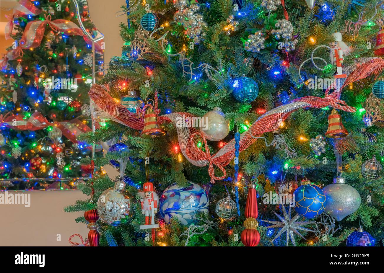 Red, white and blue decorations fill a Christmas tree and are doubled by the reflection in the mirror. Stock Photo