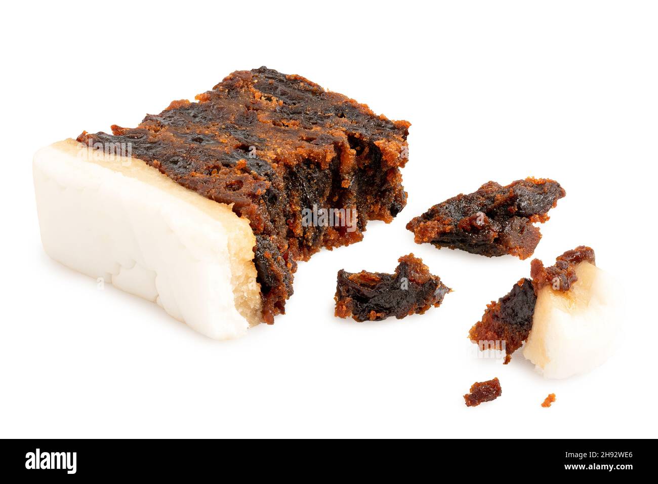 Slice of partially eaten iced fruit cake with crumbs isolated on white. Stock Photo