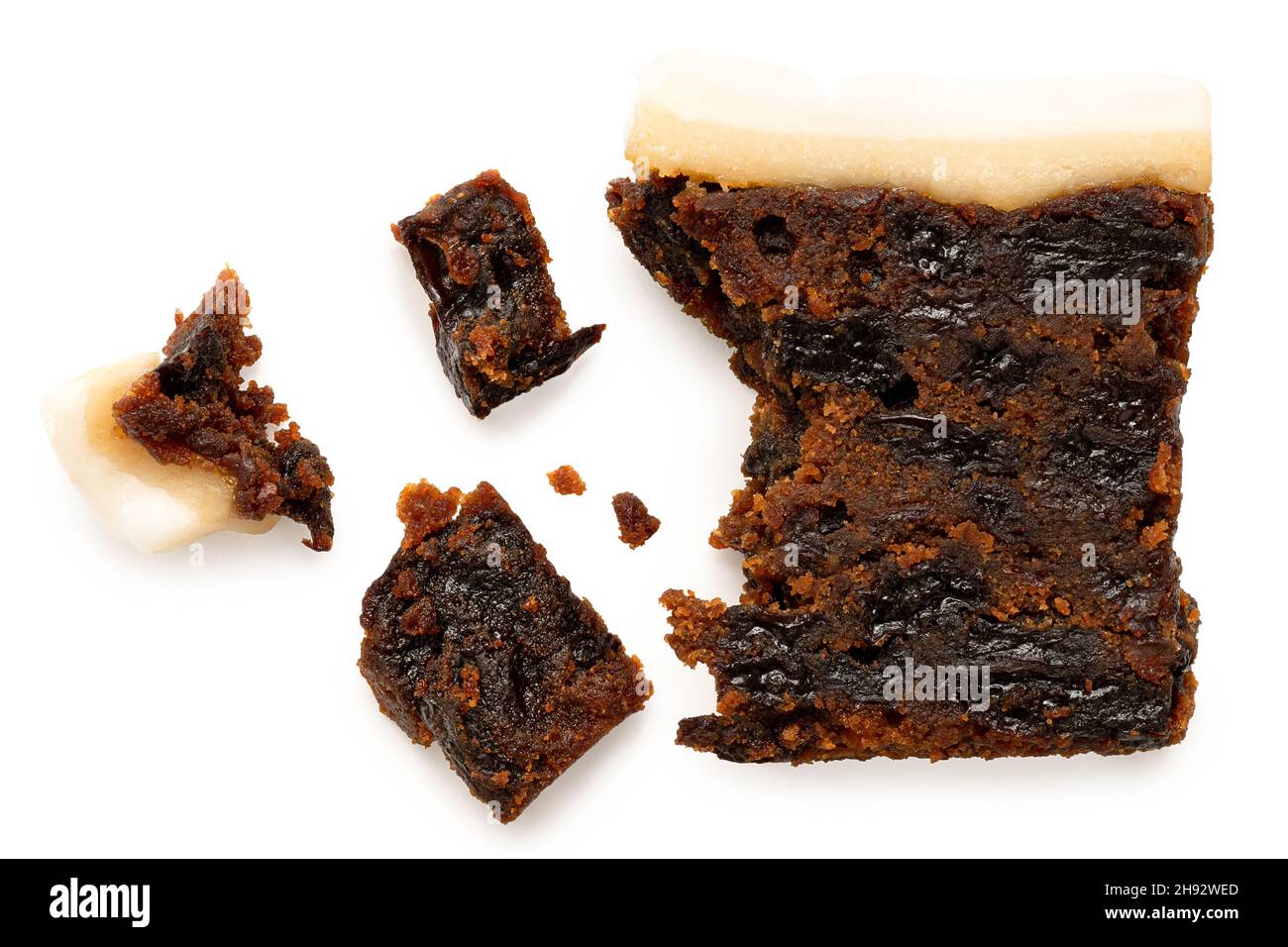 Slice of partially eaten iced fruit cake with crumbs isolated on white. Top view. Stock Photo