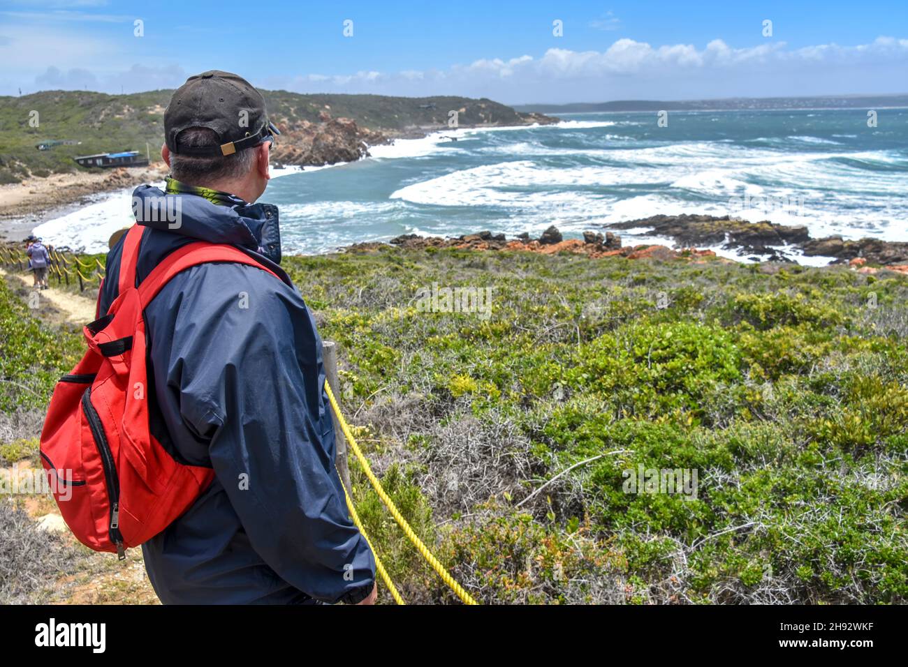 A hiker overlooking the Indian Ocean seen from the Oyster Catcher Trail near Mosselbay on the Garden Route in South Africa popular with tourists and o Stock Photo
