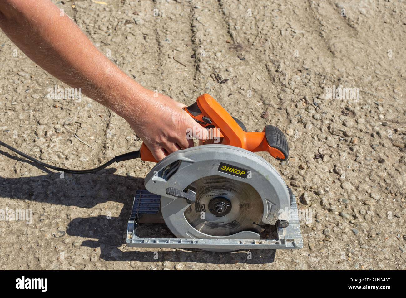 A man holds an Enkor miter saw for woodworking. translation: saw disc. Russia, Anapa - 09.24.2021 Stock Photo