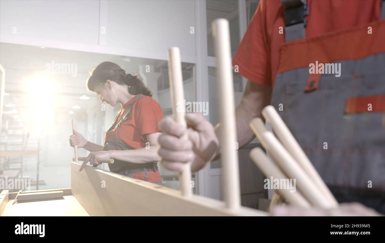 Wooden furniture mounts. Action. Closeup workers put wooden dowels in