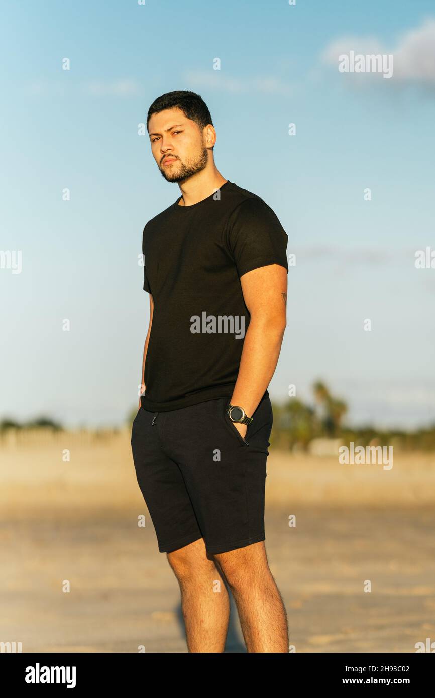 Portrait of a fit man standing on the sand of the beach with relaxed expression Stock Photo