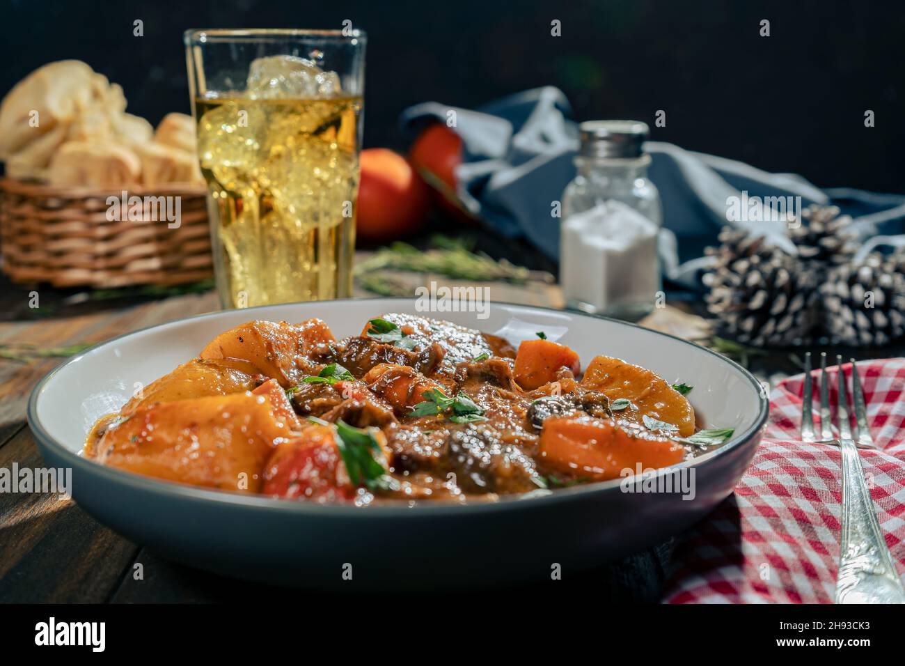 A normal view of a wooden table with a plate of meat stew with potatoes. Space for text. Horizontal orientation. Stock Photo