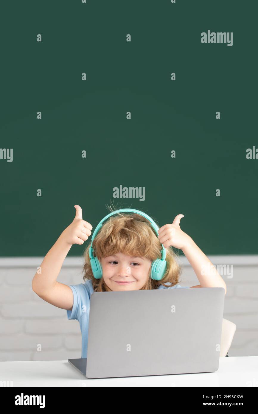 Cute boy with thumbs up wearing headphones, study with laptop in ...