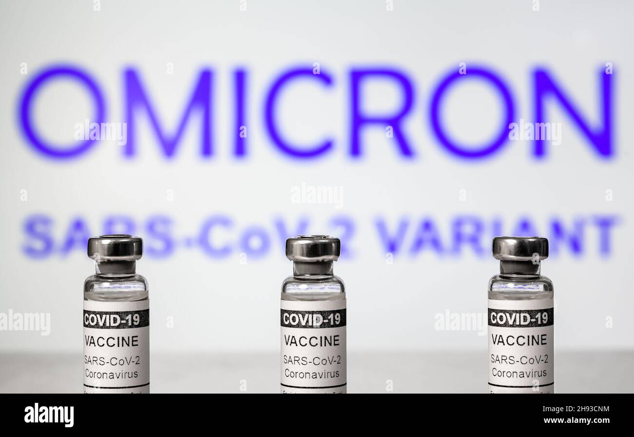 Omicron COVID-19 variant and corona virus vaccine, focus on vaccine bottles. Concept of danger, new coronavirus strains, vaccine research, reopening, Stock Photo