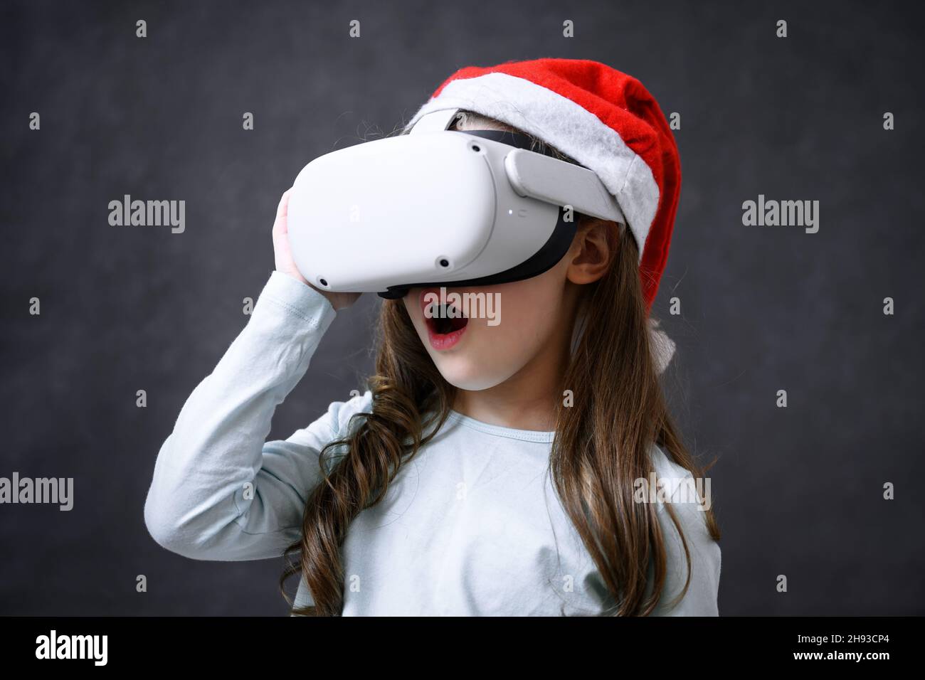Child using virtual reality headset, surprised kid looking in VR glasses. Young person with futuristic goggles having fun, little girl playing video g Stock Photo