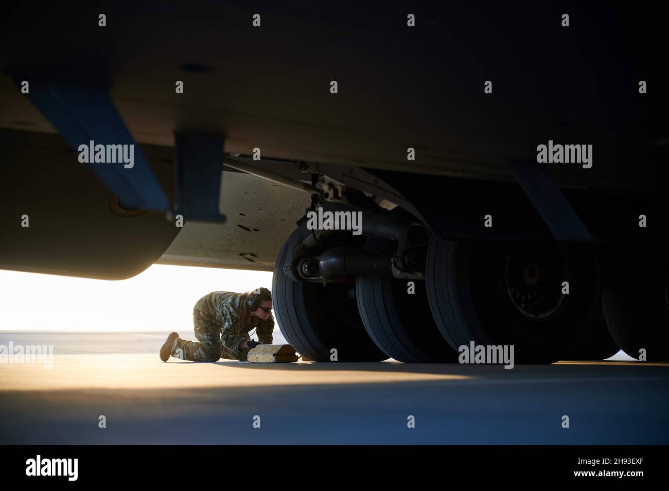 U.S. Air Force Airman 1st Class Cassie Thill, a C-17 Globemaster III aircraft loadmaster assigned to the 816th Expeditionary Airlift Squadron chocks the landing gear of a C-17 Globemaster at Al Dhafra Air Base, United Arab Emirates, Nov. 24, 2021. The 816th EAS, deployed with U.S. Air Forces Central, is responsible for delivering cargo and passengers to U.S. and partner nation forces' bases, providing airpower to U.S. Central Command. (U.S. Air Force photo by Tech. Sgt. Christopher Ruano) Stock Photo