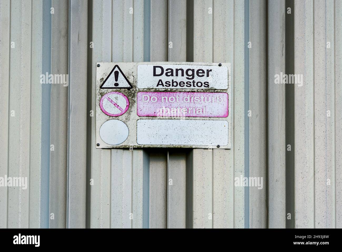 Asbestos danger sign on old galvanised shed wall. Stock Photo