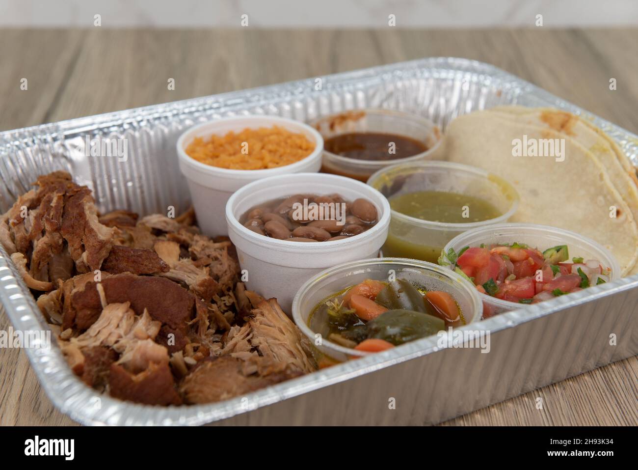 Family sized portions of carnitas pork meat with rice, beans, and salsa to have tacos for everyone. Stock Photo