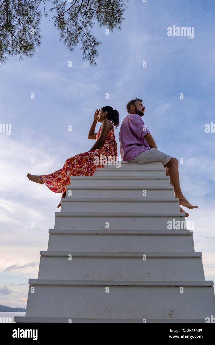 couple on a stairway with blue sky, man and woman on the white stairway in Thailand Stock Photo