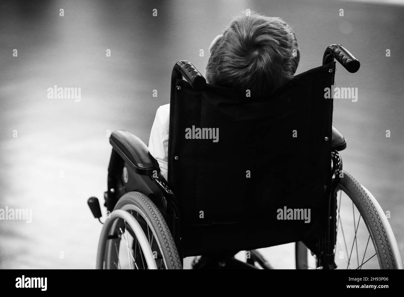 Shallow depth of field (selective focus) image with details of an ill disabled young boy in a wheelchair. Stock Photo
