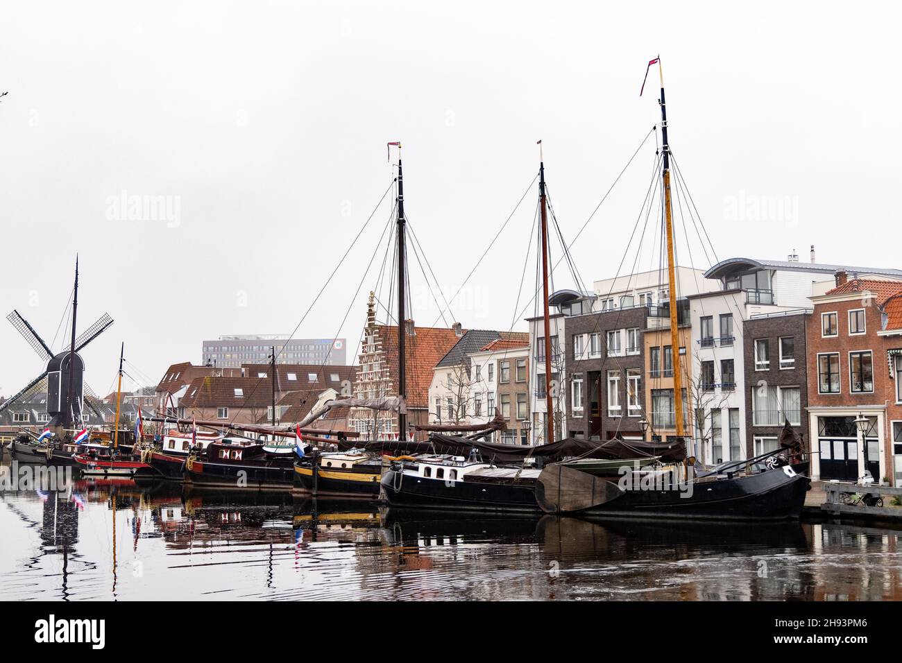 Historic boats and buildings on the Kort Galgewater on the Rhine River in Leiden, Netherlands. The Molen de Put windmill is in the background. Stock Photo