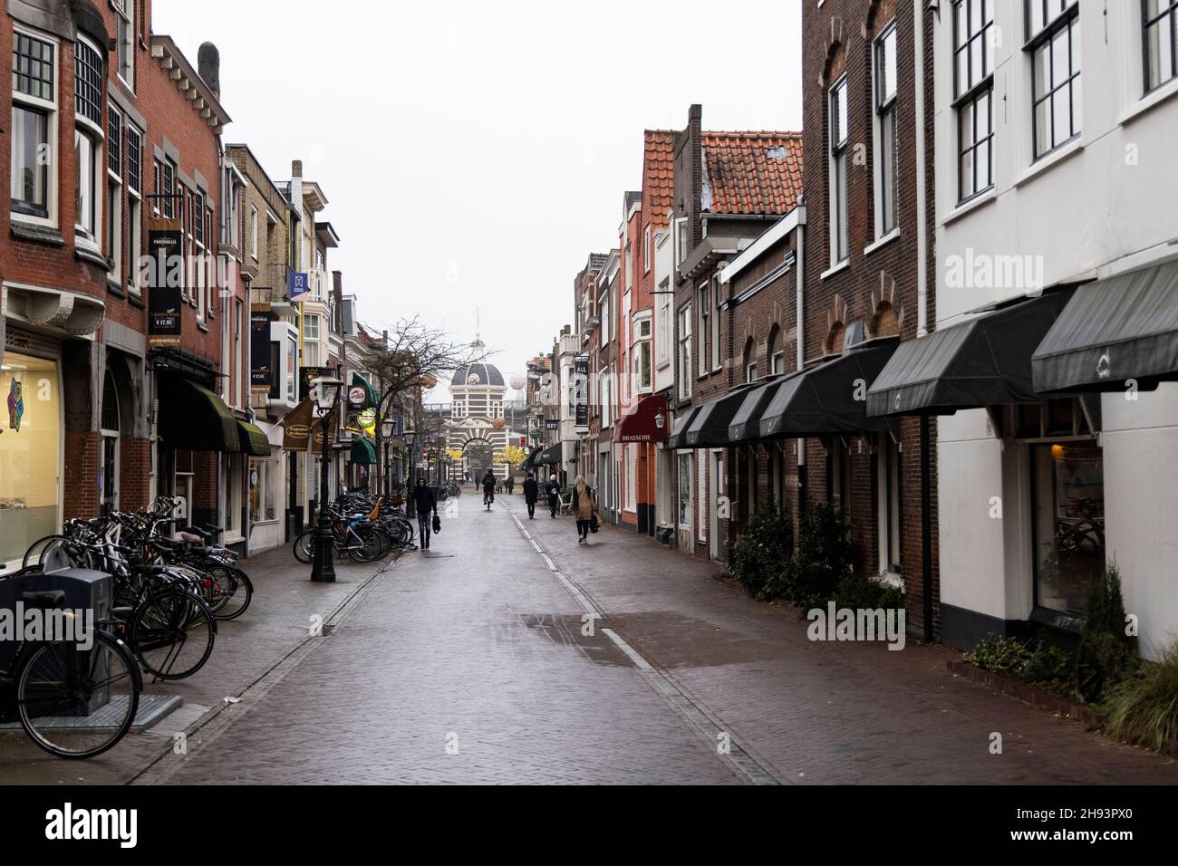 Pedestrians and bikes on Morsstraat looking toward the Morschpoort on a cloudy winter day in Leiden, Netherlands. Stock Photo