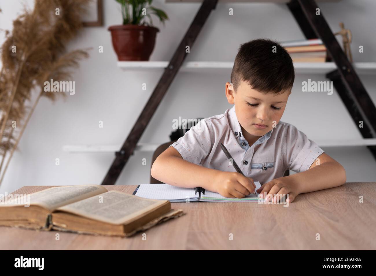 Workplace and homework of a schoolboy boy sitting at a lesson at a desk. Home school. Pupil or student preparing for tests or task. Handwritten text Stock Photo