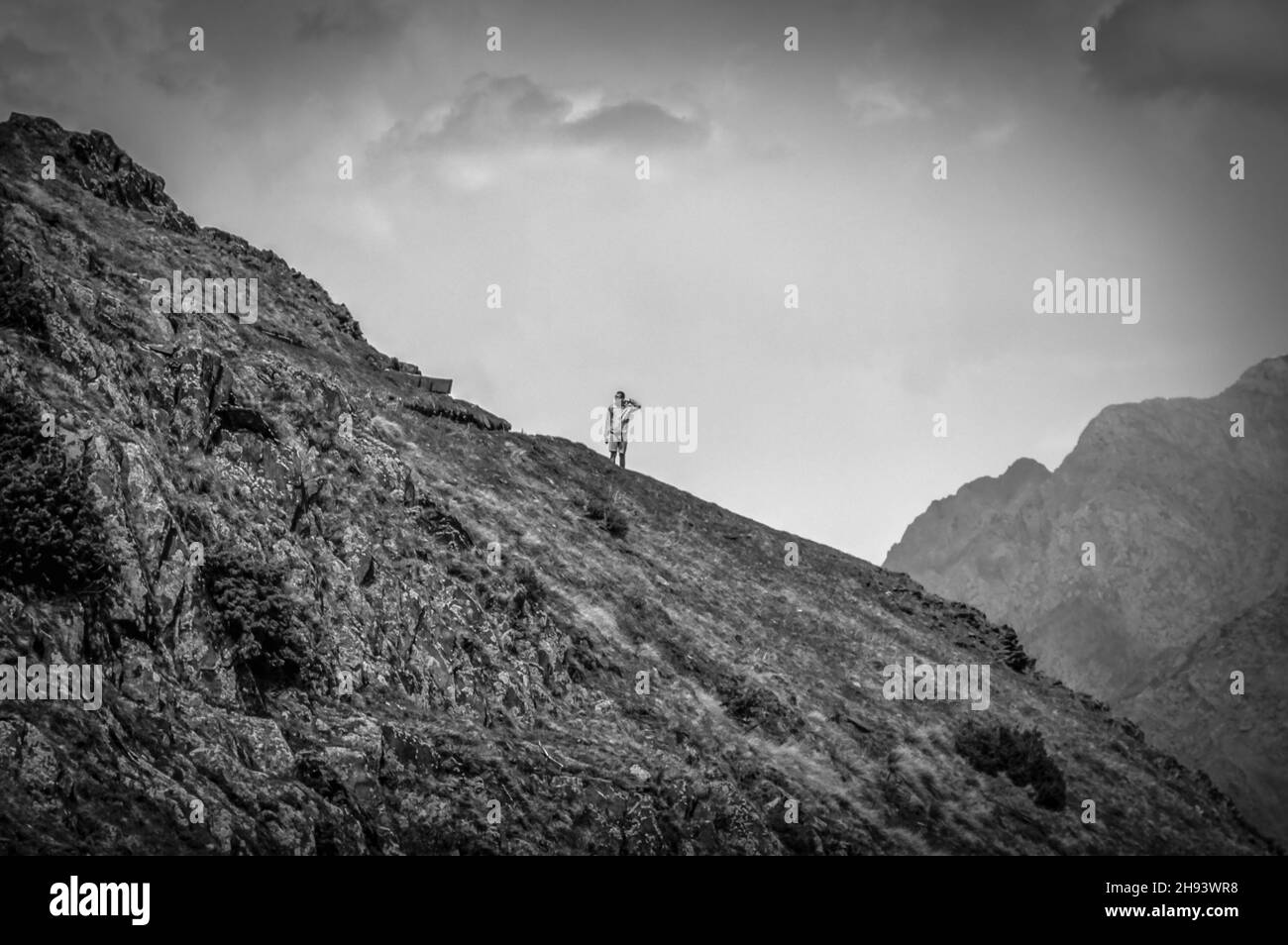 Perplexed traveller on a hiking trail in Greater Caucasus mountains against cloudy skies. Stepantsminda (Kazbegi), Georgia. Stock Photo