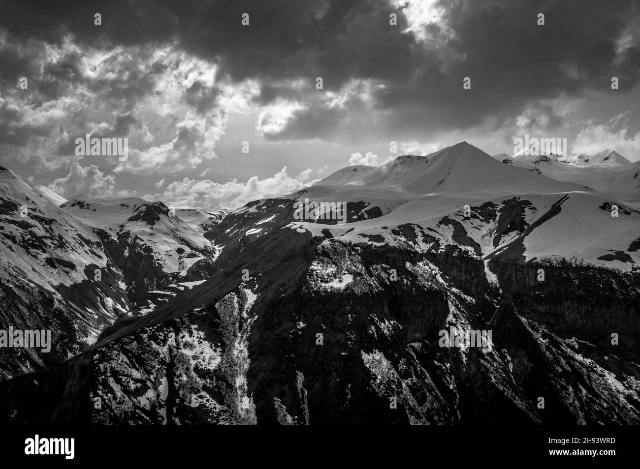 Picturesque view of Greater Caucasus mountains against stormy skies. Stepantsminda (Kazbegi), Mtskheta-Mtianeti region, Georgia. Black and white. Stock Photo