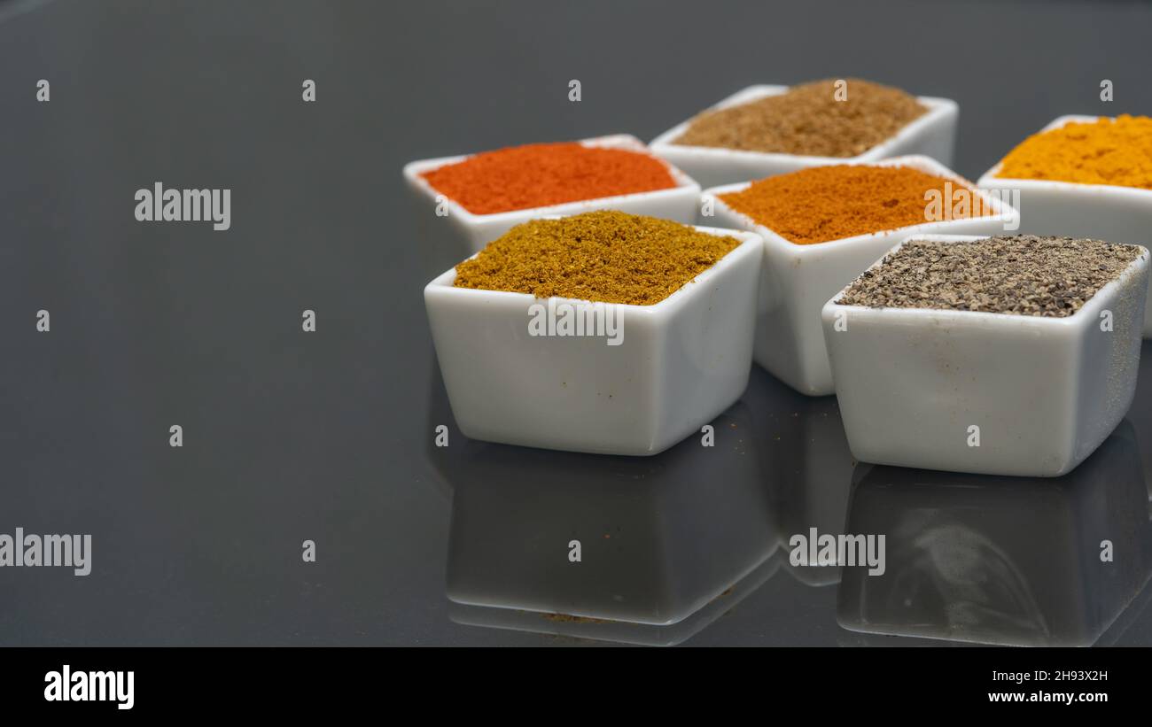 Assortment of powder spices in bowls. Selective focus. Chilli, turmeric, pepper, curry powder etc.. Stock Photo