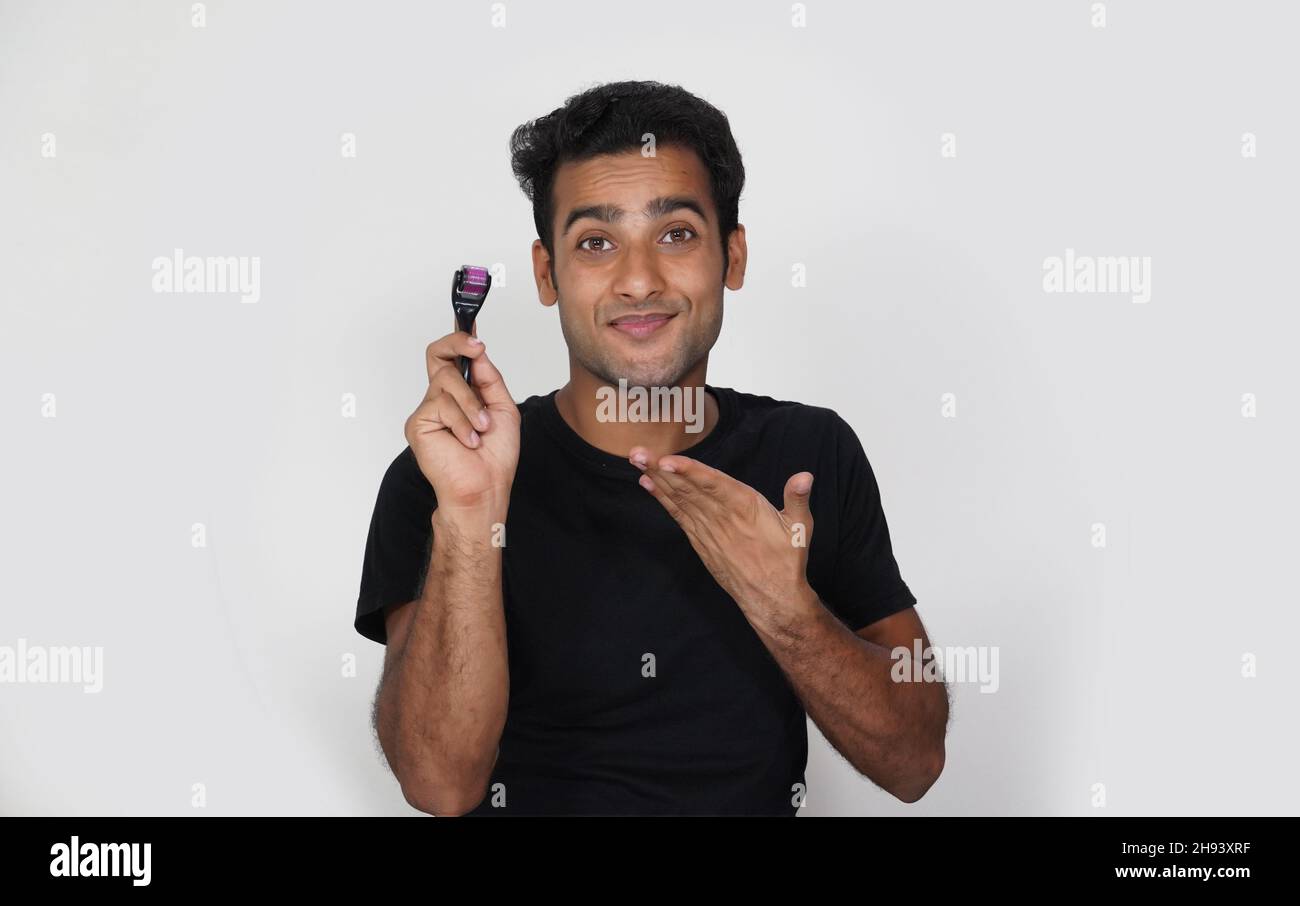 A man having using derma roller and he is happy and exited for hair growth Stock Photo
