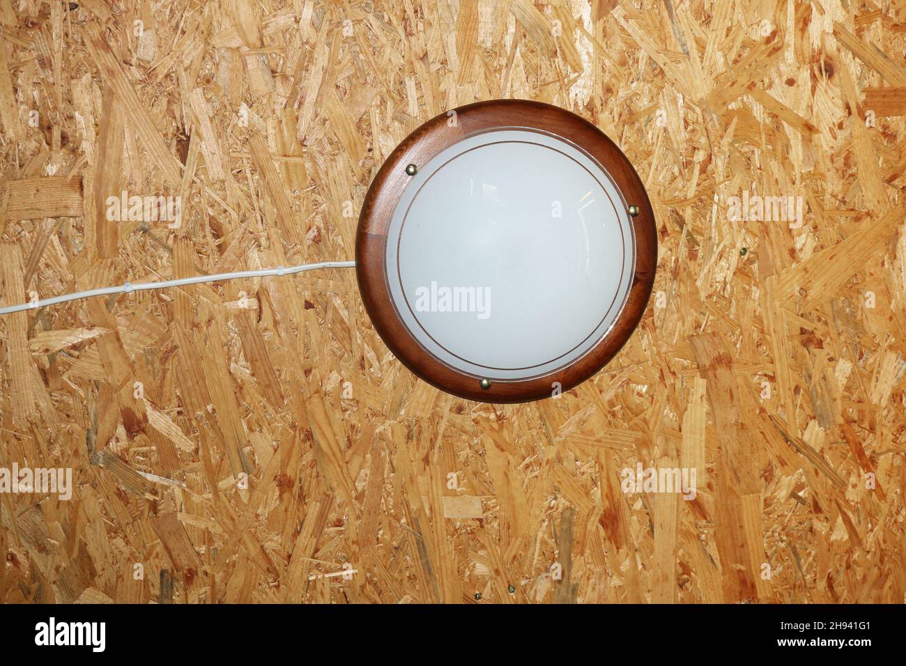 Round lamp hanging from plywood ceiling Stock Photo