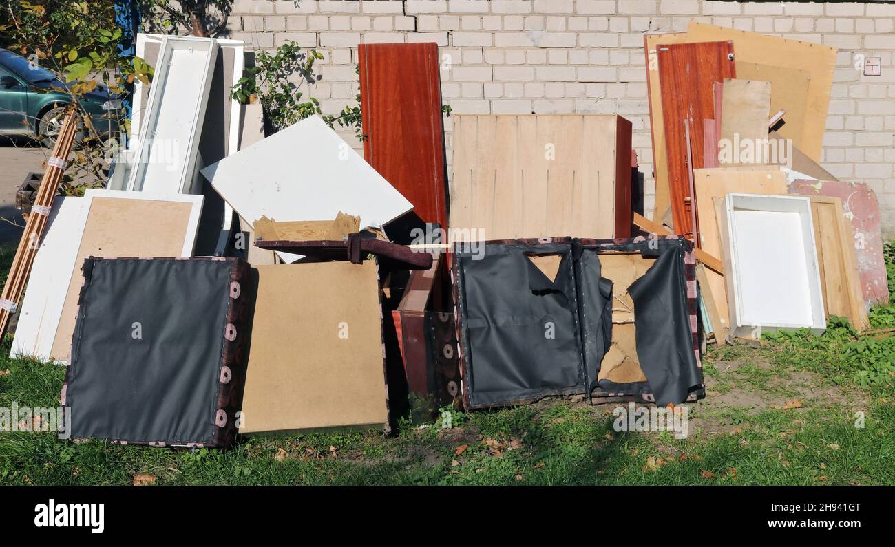 Old broken furniture at the garbage dump near the brick home Stock