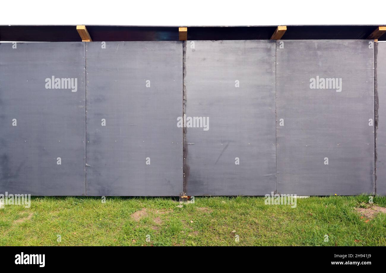 Construction site fence is made of wooden resin-impregnated black chipboards. Isolated Stock Photo