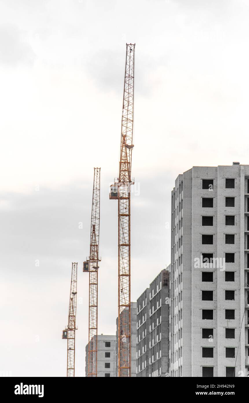 Three Construction crane on a cloudy sky Stock Photo